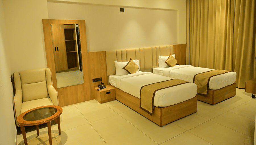 Bedroom of Bhavanis Vista By Icon featuring twin beds, a headboard, an armchair, and a door.
