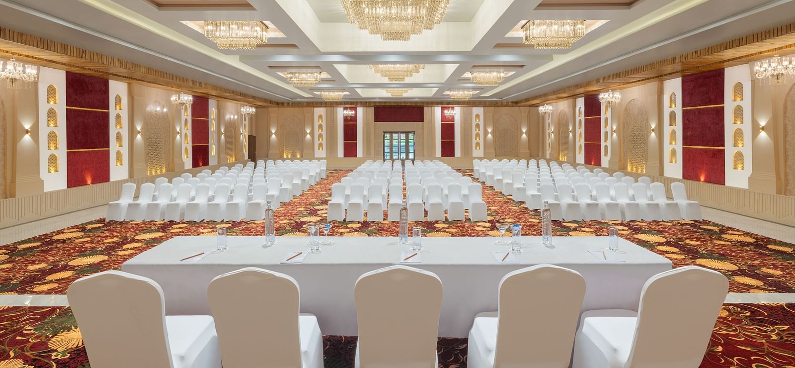 Grand Ballroom banquet with chair setting facing towards the stage with a group of chairs placed in front of a single table at A dining setting of Blue Salt and Coffee at Essentia Luxury Resort & Spa, Udaipur.. 
