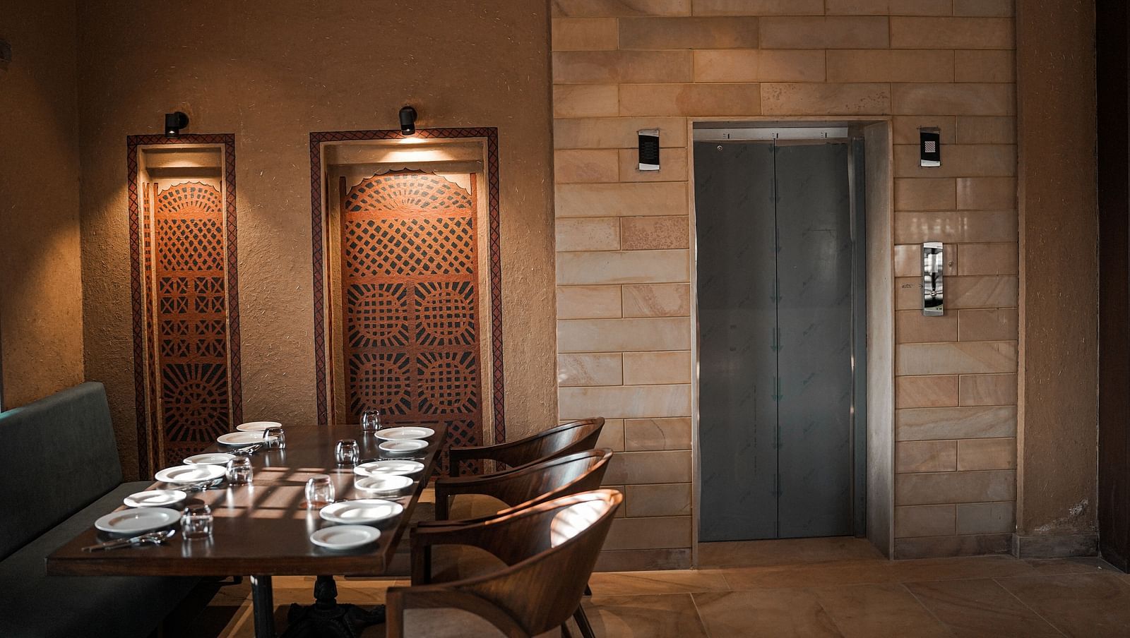 A restaurant dining area with tables and an elevator in the background at Aamaghati Wildlife Resort.