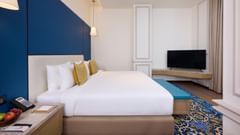 An image of our Junior Suite in Amritsar with a large bed and a television placed in the corner on a shelf - Sarovar Premiere Amritsar