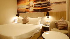 A close up shot of a bed placed beside a cosy chair and a teapoy in our hotel room in Zirakpur - Tulip Inn, Zirakpur