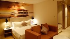 An image of our suite with an orange couch placed in front of a large king size bed - Tulip Inn, Zirakpur