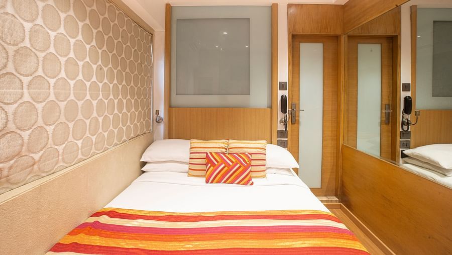 A front view of an economy room showcasing a comfy bed adorned with pillows and a blanket, creating a welcoming and cozy atmosphere.