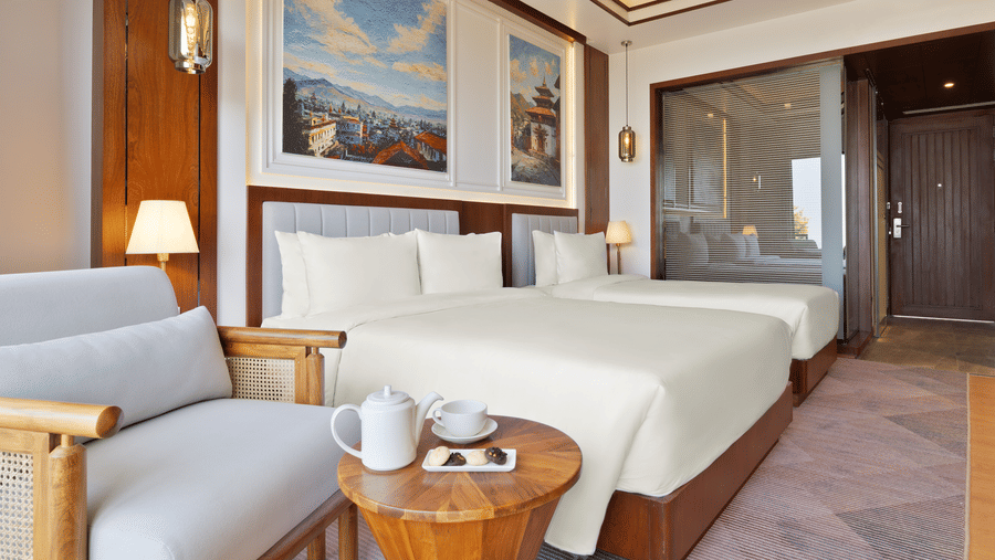 Executive Room at Royal Tulip Shivapuri National Park - Kathmandu with plush bedding, a sitting area, and framed art on the wall.