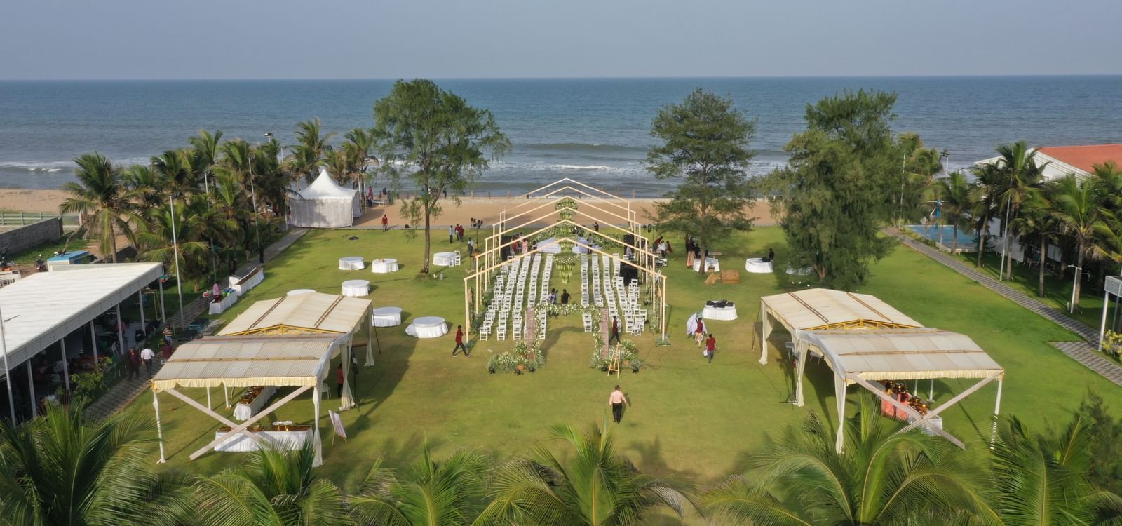 An aerial view of the lawn with decorated patios and numerous seating chairs featuring the blue sky & sea at the backdrop at Grande Bay Resort & Spa.