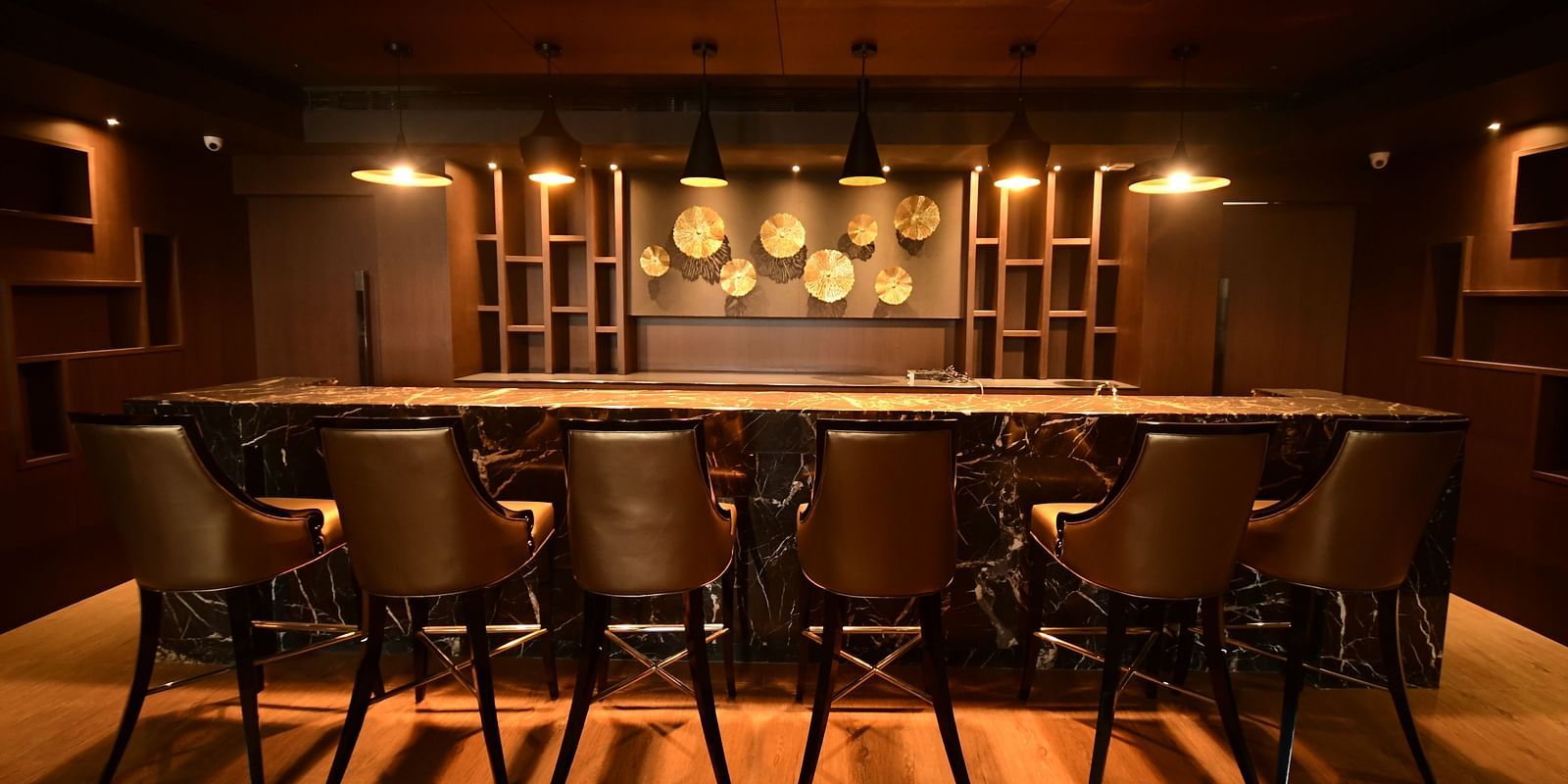 A back view of a large marble table surrounded by chairs, accented by warm lighting