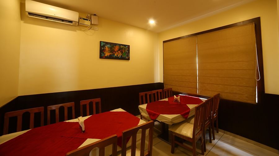 Mysore Gate Hotel, Bangalore Bengaluru A dining area featuring a nuch of chairs two tables and an ac - Mysore Gate Hotel Bangalore