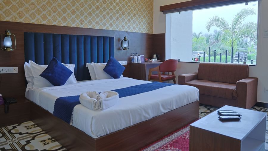 A hotel room at VITS Select Diamond Resort, Sasan Gir, with a bed, desk, and a window overlooking a lush garden.