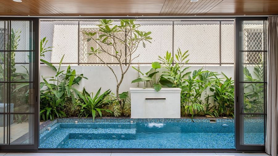 A serene pool view framed by glass walls, with lush greenery and a contemporary outdoor setting - BluSalzz Villas - Alocassia, Anjuna