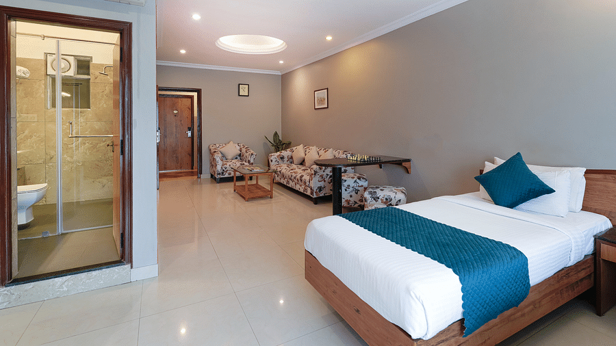  A hotel room in Bengaluru with a queen size bed, modern amenities, and a glass-partitioned bathroom - Cross Roads Inn, Bengaluru