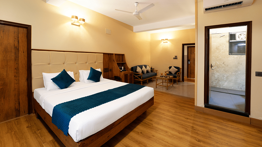 An Executive Room with a queen size bed, a seating area, a bathroom, and stylish decor - Cross Roads Inn, Bengaluru