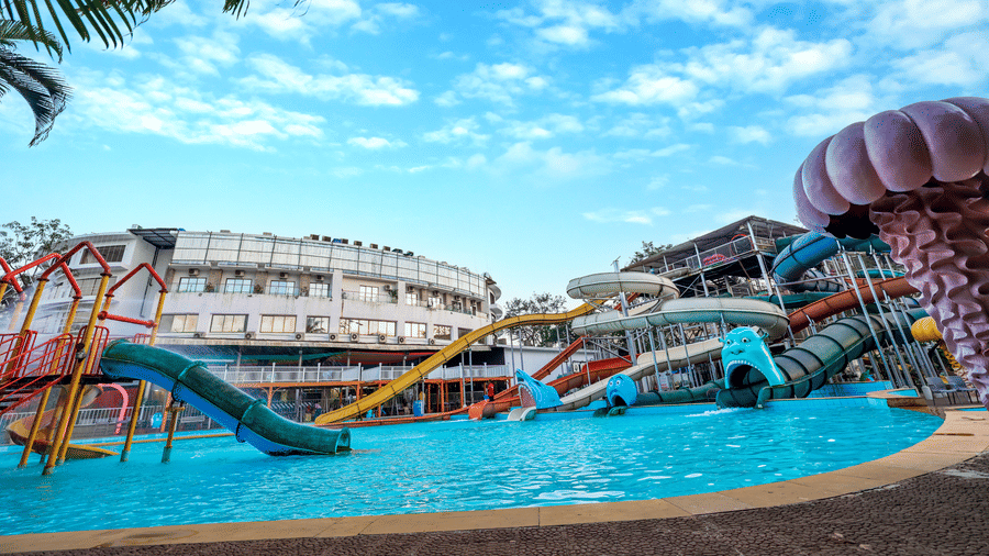 Section of the water park showing the edge of the pool with a large, themed feature structure and tropical landscaping at Kumar Resort by Turtle.