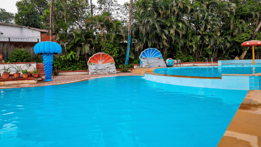 View of a shallow swimming area with decorative mushroom-shaped water features and surrounding tropical greenery at Kumar Resort by Turtle.