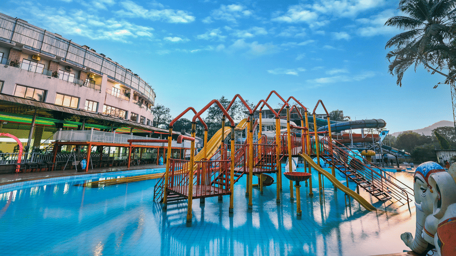Expansive view of the water park featuring multiple themed structures, slides, and pools, with the resort building visible behind the water features at Kumar Resort by Turtle.
