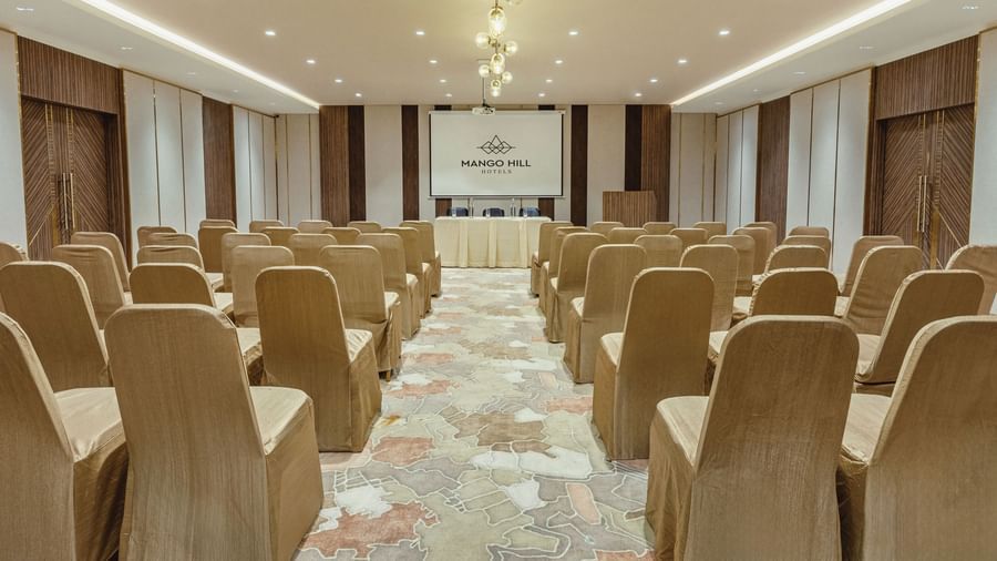 Banquet hall at Mango Hill Central, Chennai, with chairs arranged in rows facing a screen and a table at the front. The room is set up in a theatre style.