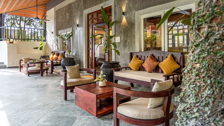 A covered patio with dark wood furniture, potted plants, and a textured ceiling - Mango Hill Resort, Coimbatore