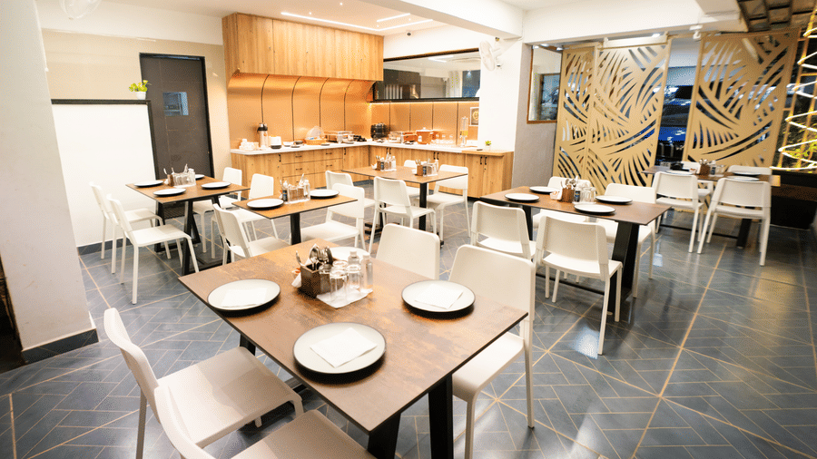 Restaurant seating area with tables and chairs set for dining at Sunrise Business Hotel, Hyderabad.