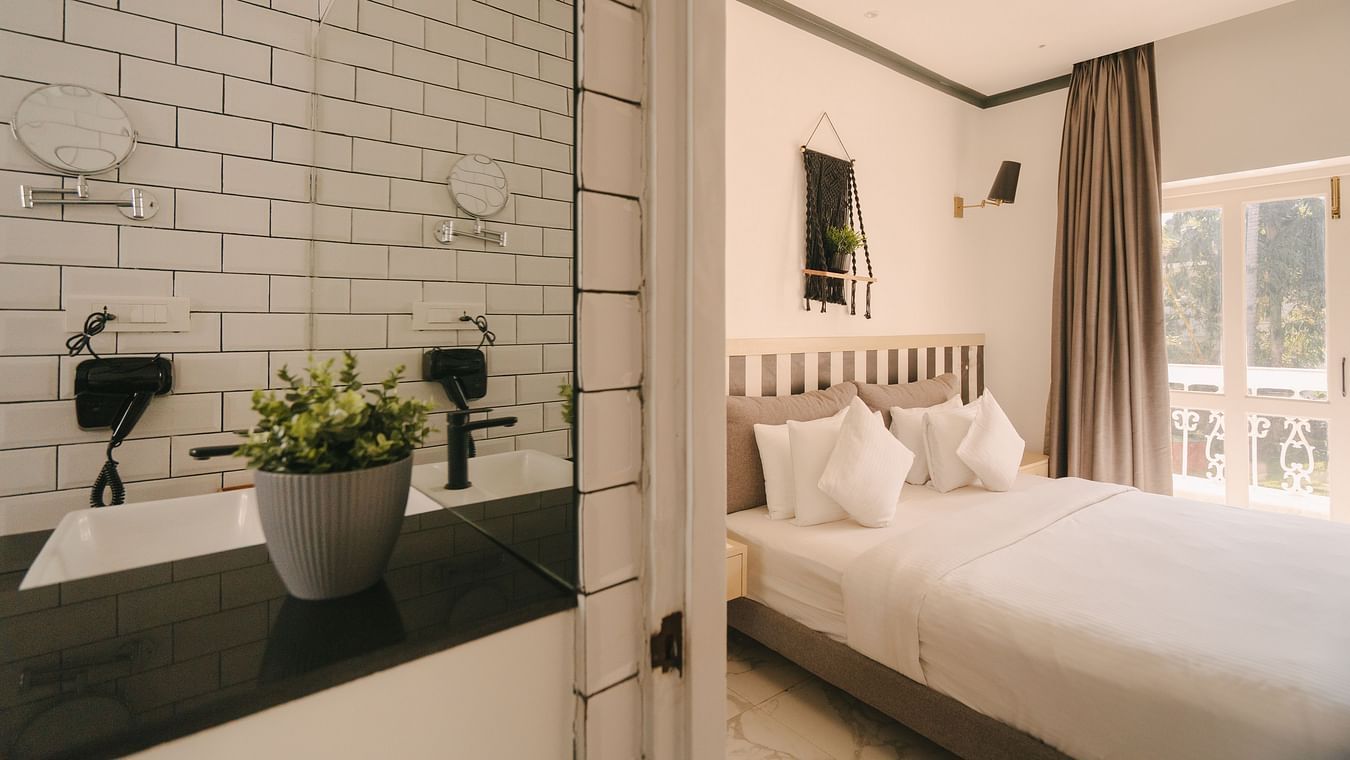 Contemporary bedroom with white interiors and a plant-themed decor at Richmonde Ananta Elite, Goa.
