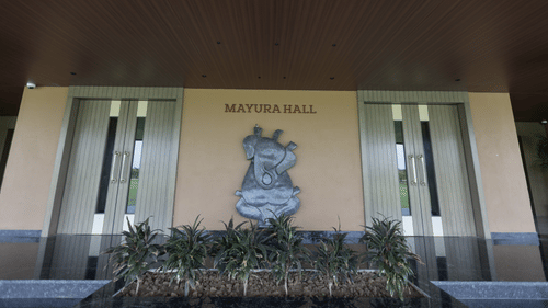 The entrance of Mertura Hall at Pride Resort, Jodhpur, featuring a decorative emblem and flanked by glass doors.