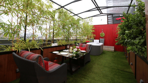 An image of a cafe featuring chairs and tables surrounded by plants and glass ceilings  | Theory9 - Premium Service Apartments, Bandra
