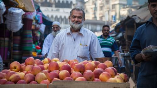 A man smiling and selling fruits in a cart