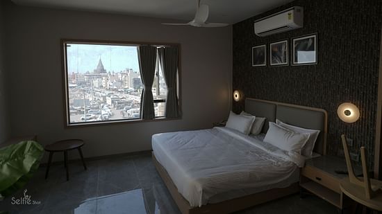 Deluxe Room at Pride Comfort, Dwarka with a double bed and view of the city from the windows