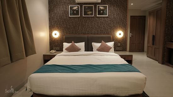 Premium Room at Pride Comfort, Dwarka with a double bed and side tables