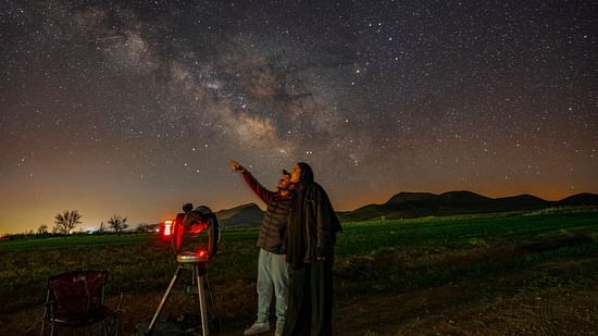 Two people admiring the star with a telescope in front