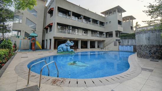 A building overlooking the pool and landscaped surroundings at VITS Lonavala.