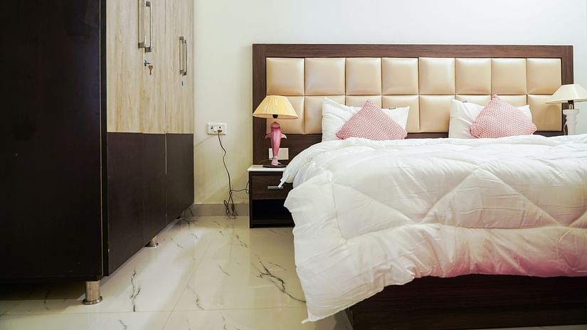 An image of a bedroom featuring a double size bed, a bedside table with lamp, and a wardrobe - Lime Tree 2BHK Service Apartment Near Artemis Gurgaon