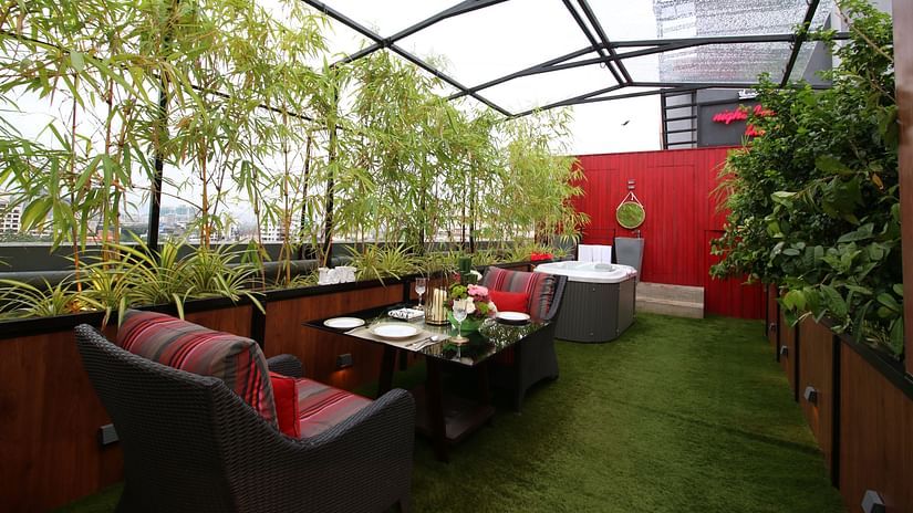 An image of a cafe featuring chairs and tables surrounded by plants and glass ceilings  | Theory9 - Premium Service Apartments, Bandra