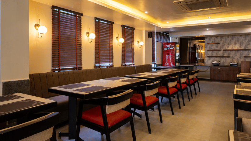 The dining section at VITS Select, Bengaluru, featuring upholstered bench seating with individual tables and chairs.