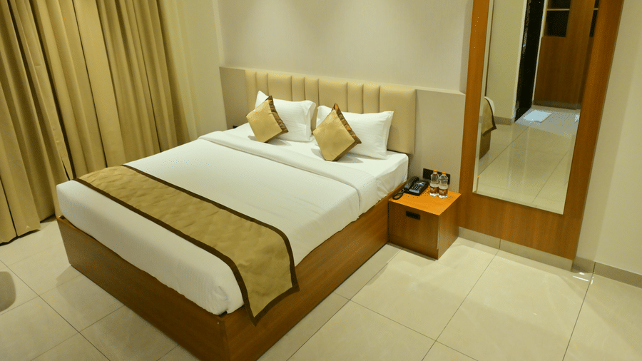 Bedroom of Bhavanis Vista By Icon featuring a bed, a headboard, a mirror, and a bedside table.