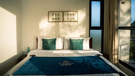A bedroom with sunlight streaming through the windows at BluSalzz Escapade Resort, Lansdowne.