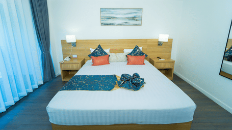 Plush king size bed with warm-toned night lamps on wooden bedside tables in a room with cream walls and soft white linens | Hotel 39 - Hotel in Montego Bay