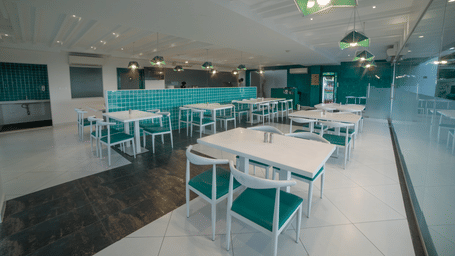 Bright restaurant with white tables, teal chairs, and minimalist decor in one of the best restaurant near Palani Temple | Regency Palani by GRT Hotels
