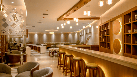 An open plan bar lounge showing a counter with wooden stools, a wooden room partition, and low casual seating options at Tiara by MPS.
