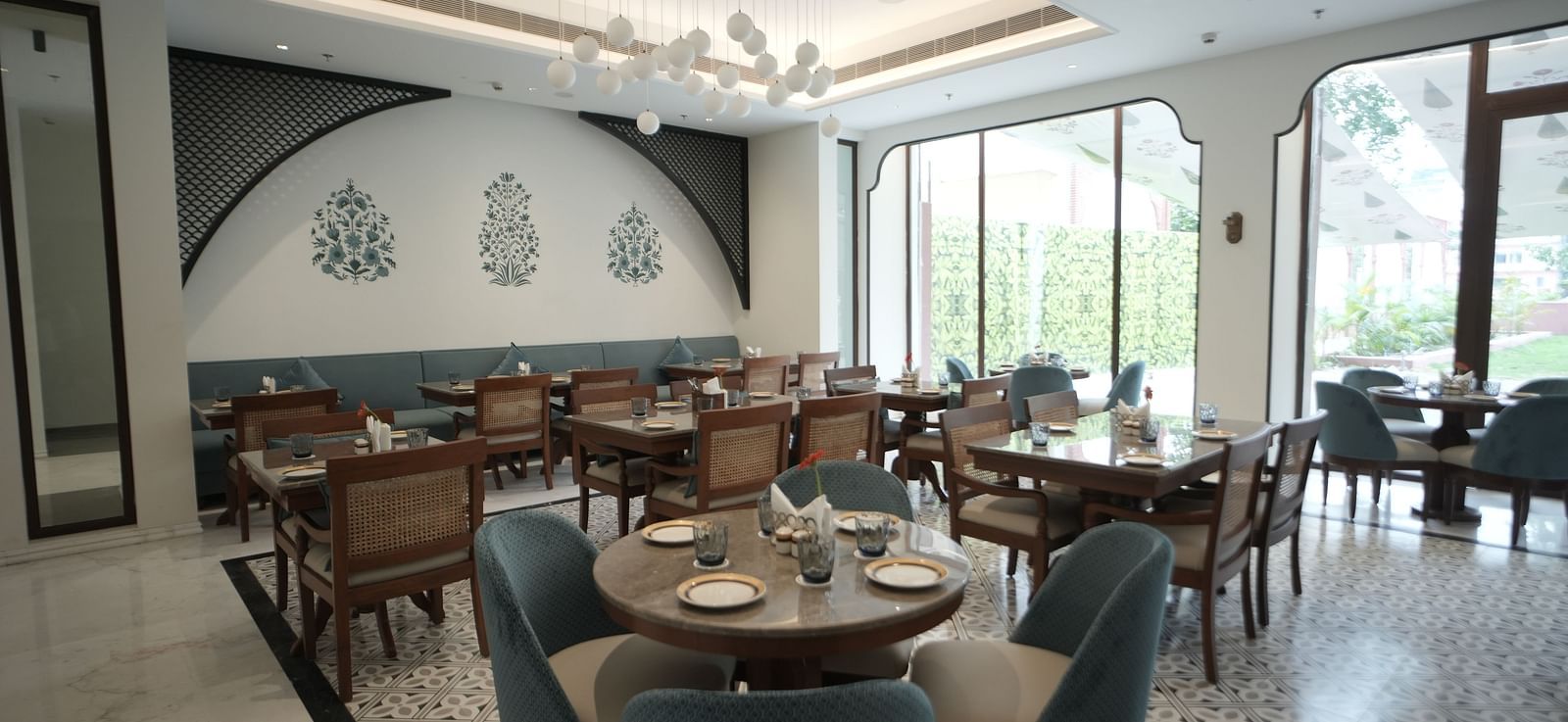 A brightly lit dining area with ample of natural lighting coming from the huge windows in the corner at Bhagirathi by RDB Atishay.