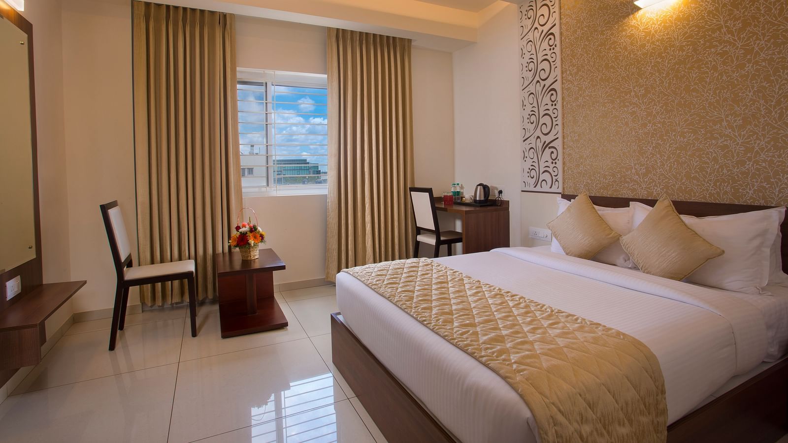 A hotel room with a comfortable bed, a wooden side table with flowers and a city view through the window - De Venetian by TGI, Brookefield