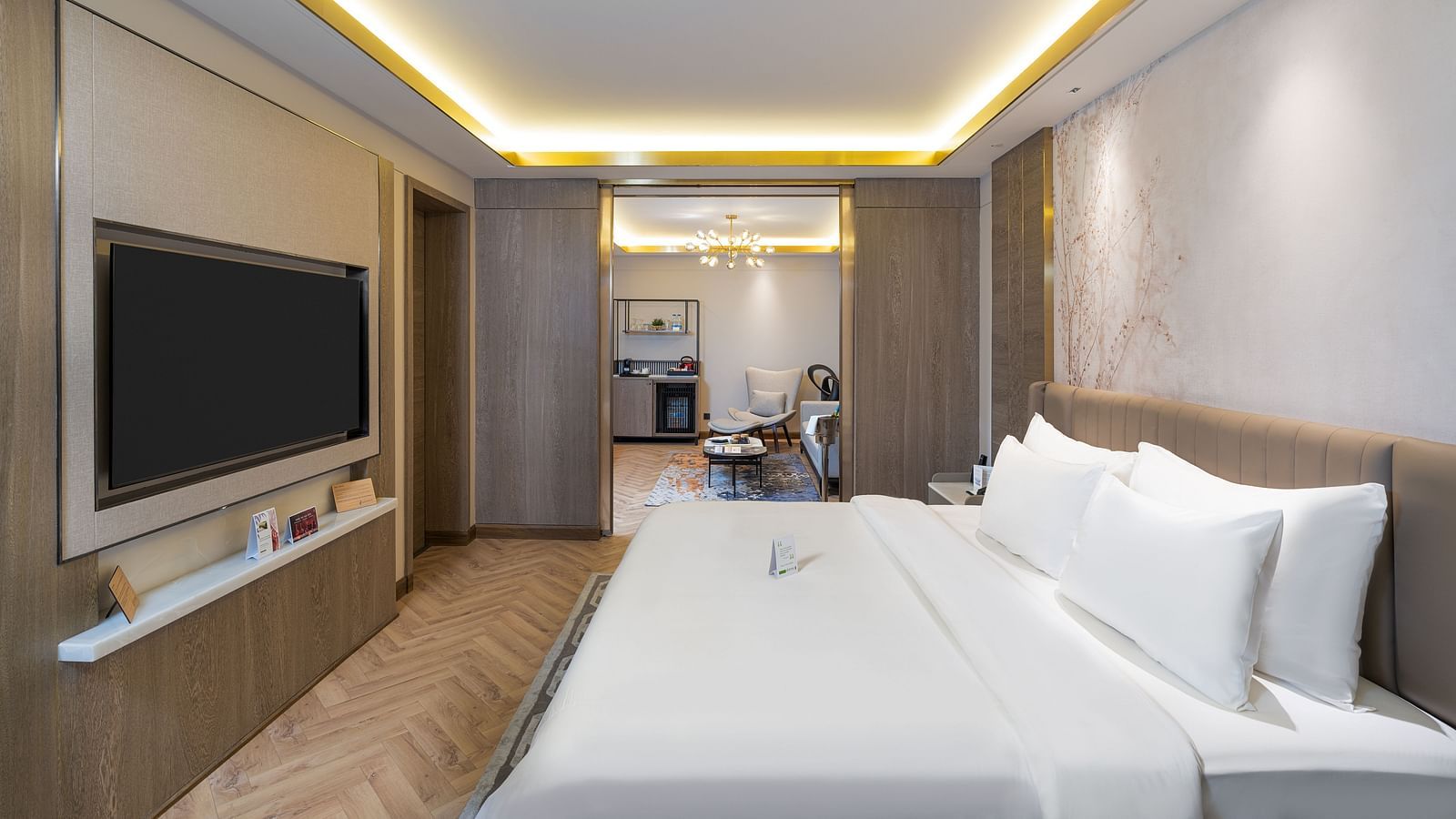 Luxurious Nirvana Suite bedroom featuring a king size bed, wall-mounted TV, subtle ambient lighting, and a glimpse into the suite layout - Nirvana Luxury Hotel, Ludhiana