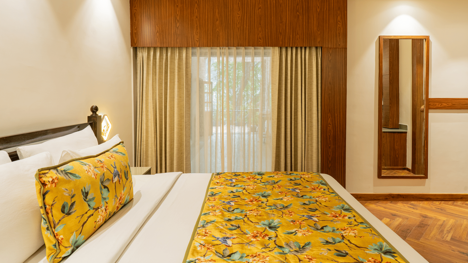 A well-lit bedroom featuring a bed, a mirror on a wall, and opaque and sheer curtains | Summit by the Ganges Beach Resort & Spa, Rishikesh