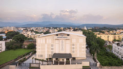 A facade image of MJ Sarovar Portico with a backdrop of city and mountain views - MJ Sarovar Portico, Haridwar