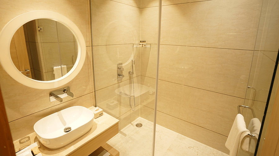 bathroom with a round mirror and glass cubicle