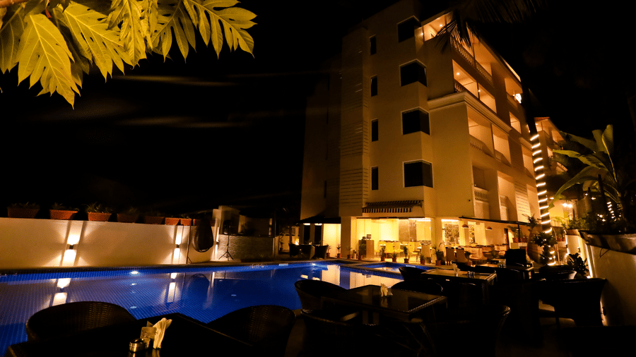 An exterior of a multi-storey building of Amara Grand Baga, Goa, with a swimming pool on the side.