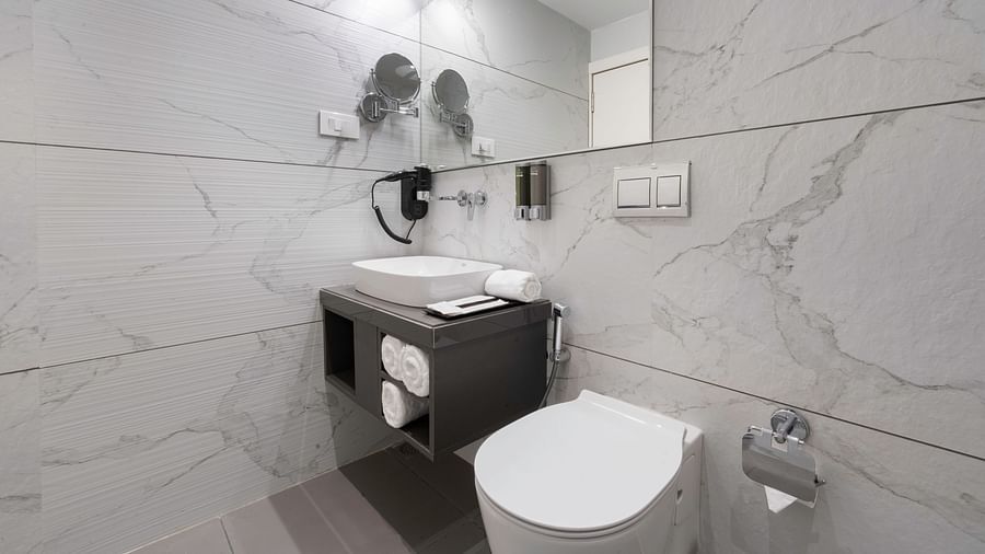 Clean and modern bathroom featuring white marble-like tiles and a floating sink - Clarks Inn, Indore