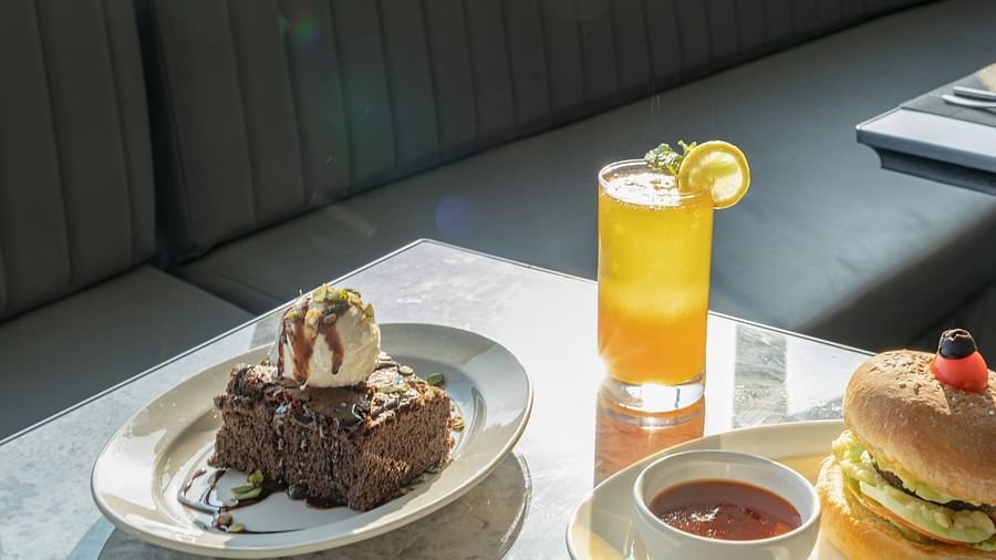 Chocolate brownie topped with ice cream next to a tall glass of orange juice on marble surface at Clarks Inn Suites, Hyderabad