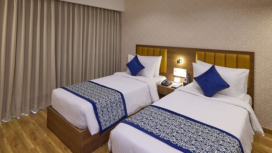 A stylish hotel room with twin beds and floor-to-ceiling curtains - Grand Continent, Brookefield