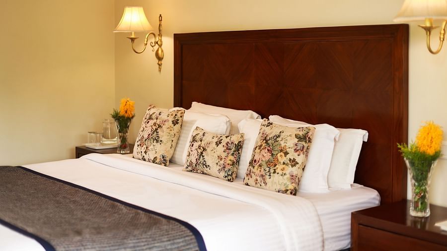 Closer view of a beautifully tucked bed with soft lines and pillows along with bedside lamps - Lamrin Norwood Green, Palampur