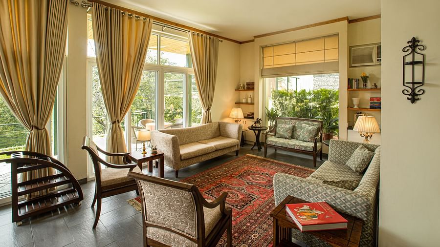 side angle view of a spacious living room with modern interior decor and large windows facing the tea gardensLiving RoomLiving Room2 - Lamrin Norwood Green Palampur