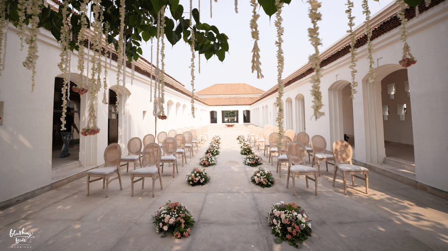 A wedding lawn at Marasa Sarovar Premiere Bodhgaya featuring sets of chairs on either side and a pathway in between where bouquets are placed.